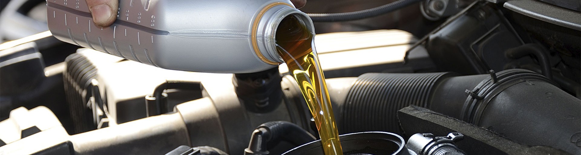 New gold-colored motor oil poured into a car engine