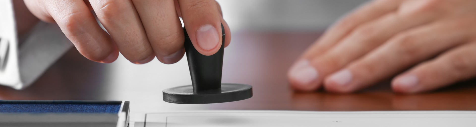 Close-up of a hand that is lowering a stamp onto a piece of paper