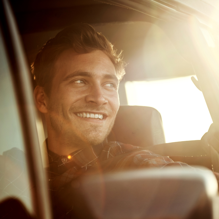 Smiling handsome man drive his car at sundown