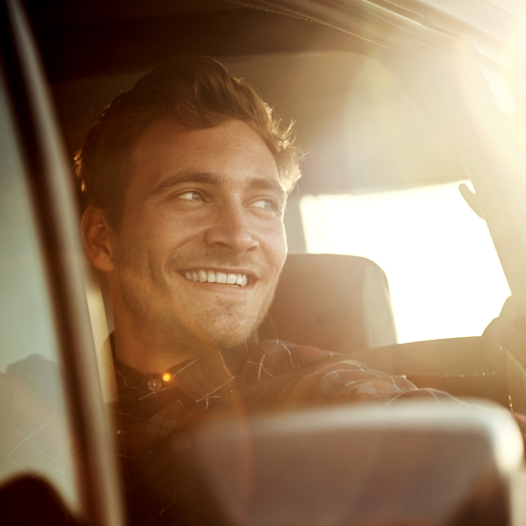 Homme heureux qui conduit sa voiture au couché du soleil